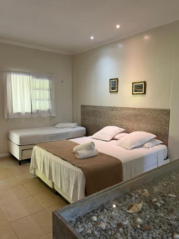 a bedroom with two beds and a window at Suites Prime Itamambuca in Ubatuba