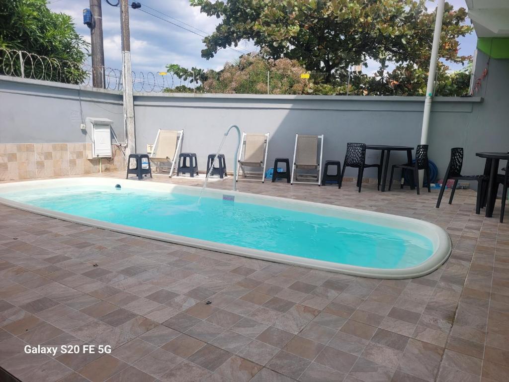 a large swimming pool with chairs and a table at Unidades 1 e 2 e 3 Pousada do Sossego Mar e Verde in Itanhaém
