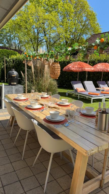 a wooden table with plates and glasses on it at Villa June Rosy in Wijchen