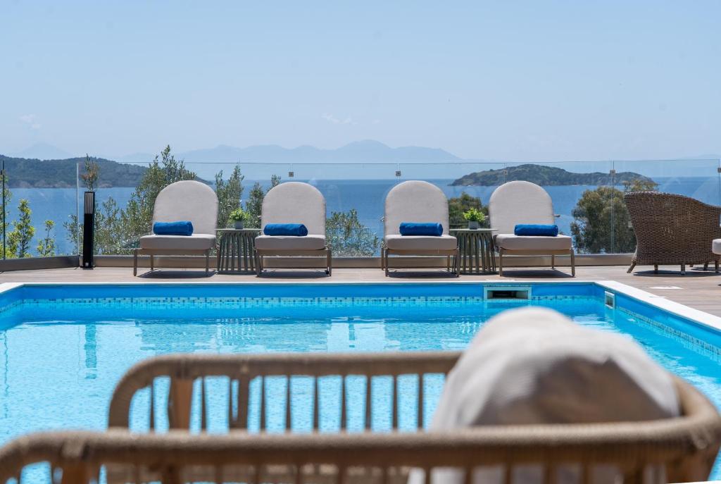 a swimming pool with chairs and the ocean in the background at Irida Aegean View, Philian Hotels and Resorts in Megali Ammos