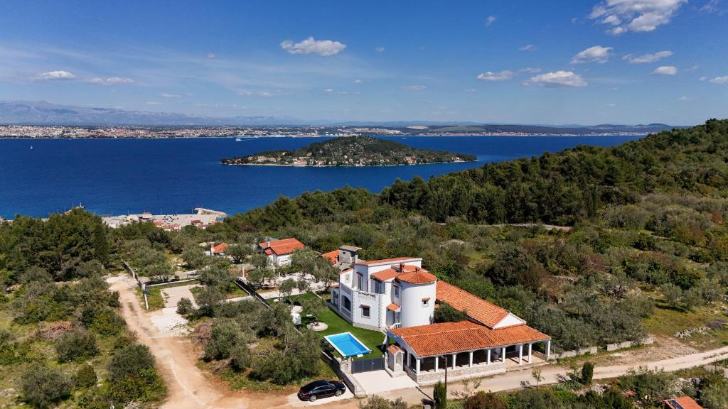 an aerial view of a house on a hill next to the water at Costa apartment with private pool in Preko