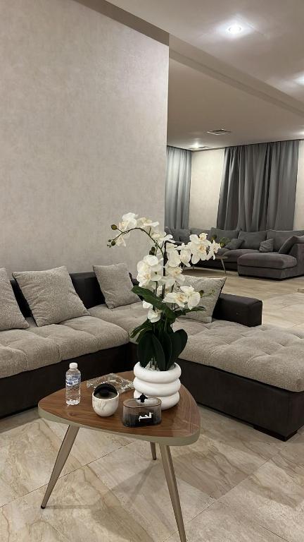 ein Wohnzimmer mit einer Couch und einem Tisch mit Blumen in der Unterkunft Luxury A2 Chalet COMO in Al Khīrān