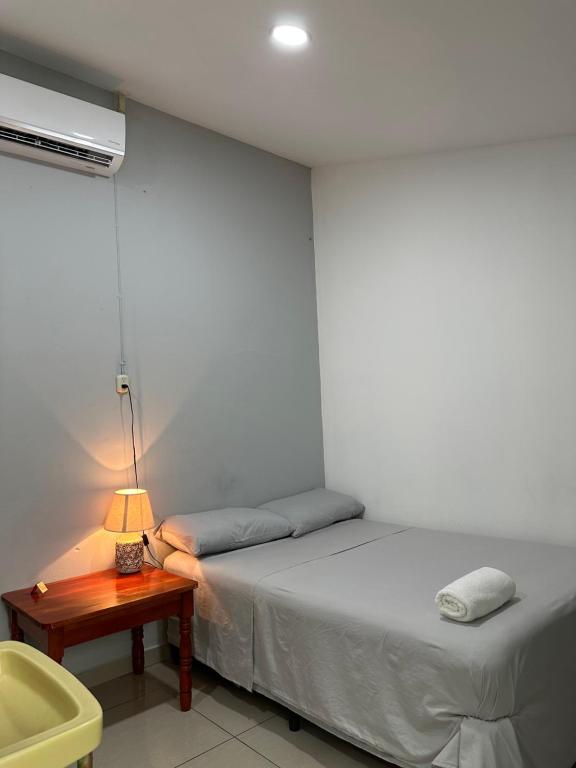 a bedroom with a bed and a table with a lamp at Hostal El Amate #1 in Suchitoto