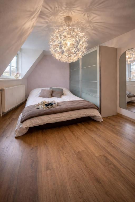 a bedroom with a large bed and a chandelier at Escapade chaleureuse in Sequedin