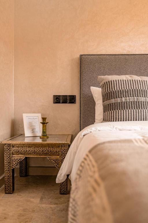 a bedroom with a bed and a table with a book on it at Prime location Moroccan-Style Luxury Apartment with Parking near Carré Eden Shopping Center in Marrakesh