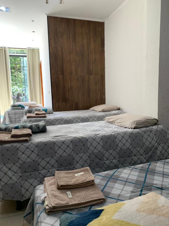 a room with three beds with towels on them at Hotel Airton in Ivaiporã