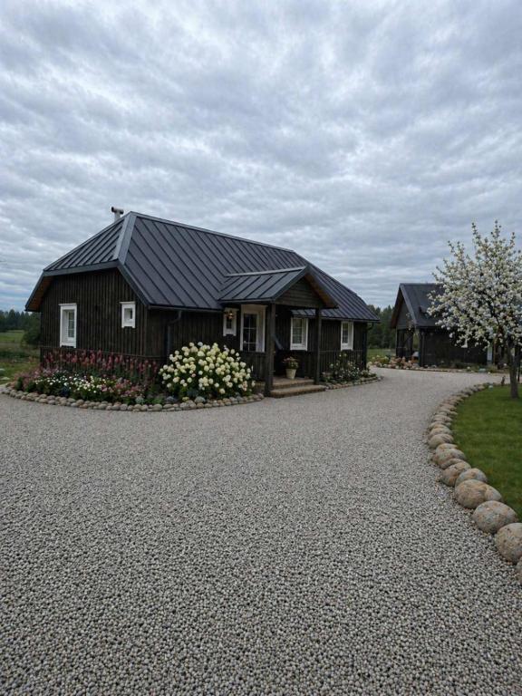 a house with a black roof on a gravel driveway at Kregžlės kaimas in Skirlėnai