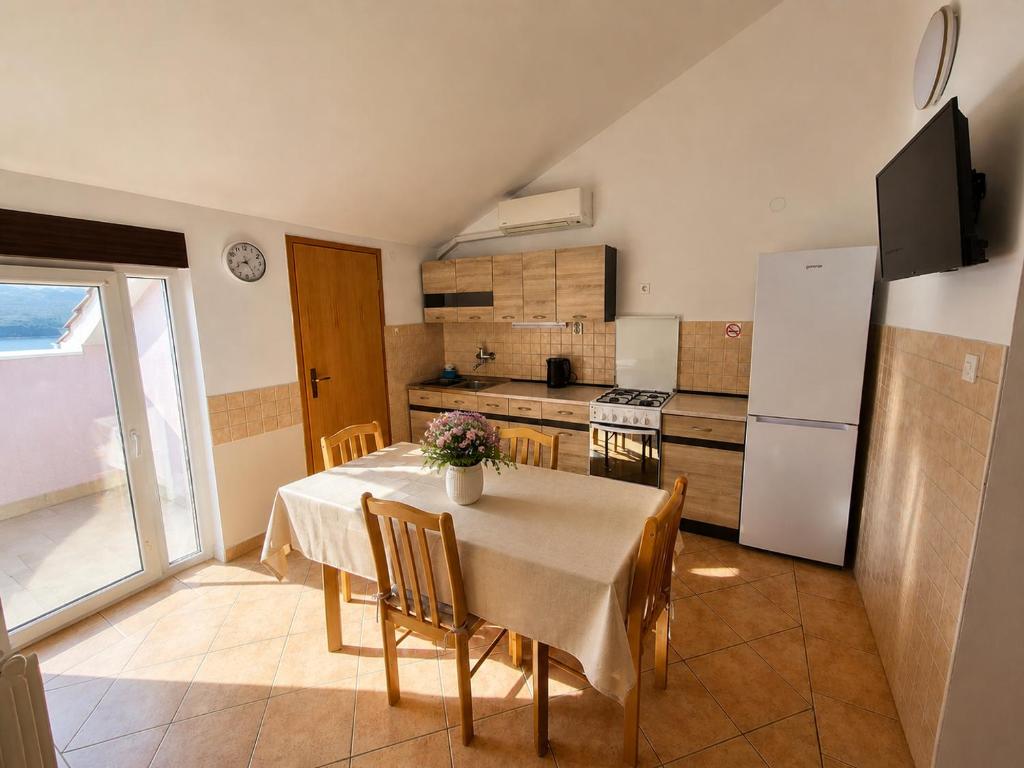 a kitchen with a table with chairs and a refrigerator at Apartments Izabela Mužić-Fornarić Cres in Cres