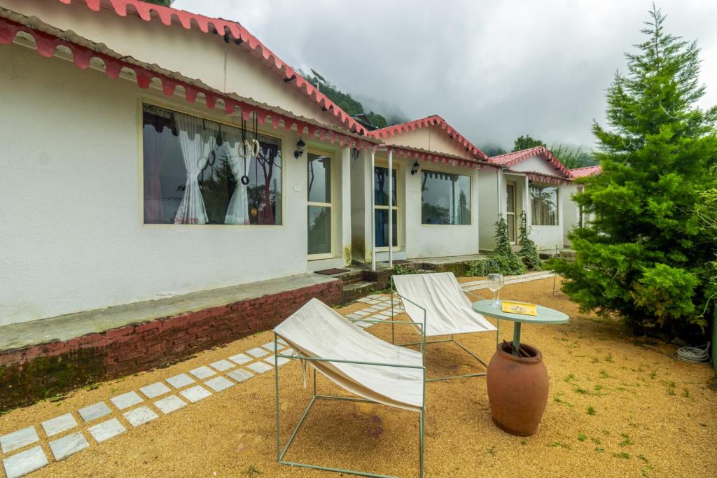 two chairs and a table in front of a house at THHPSOCIETY - Taha Cottages in Bhīm Tāl