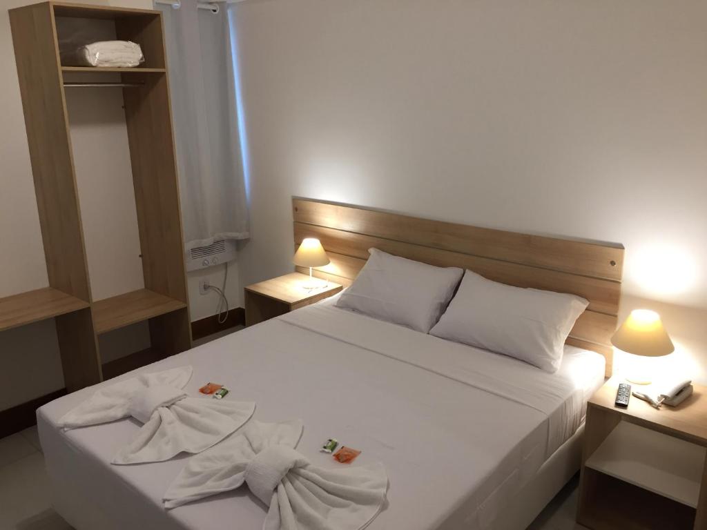 1 dormitorio con 1 cama blanca y 2 toallas en Pousada Vila Forte, en Cabo Frío
