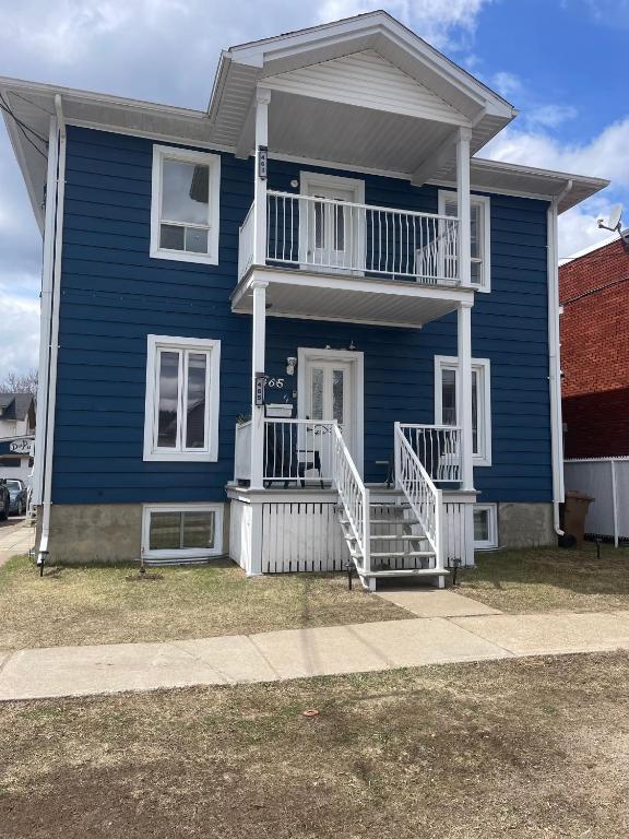 a blue house with white railings and a porch at Condo DidiPier in La Tuque