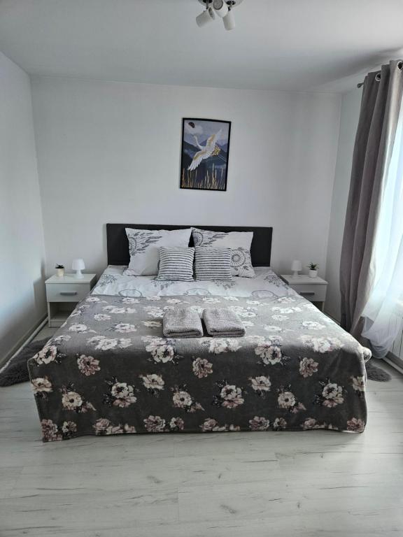 a bedroom with a large bed with a floral blanket at Apartament Wiejska Sielanka in Ryn