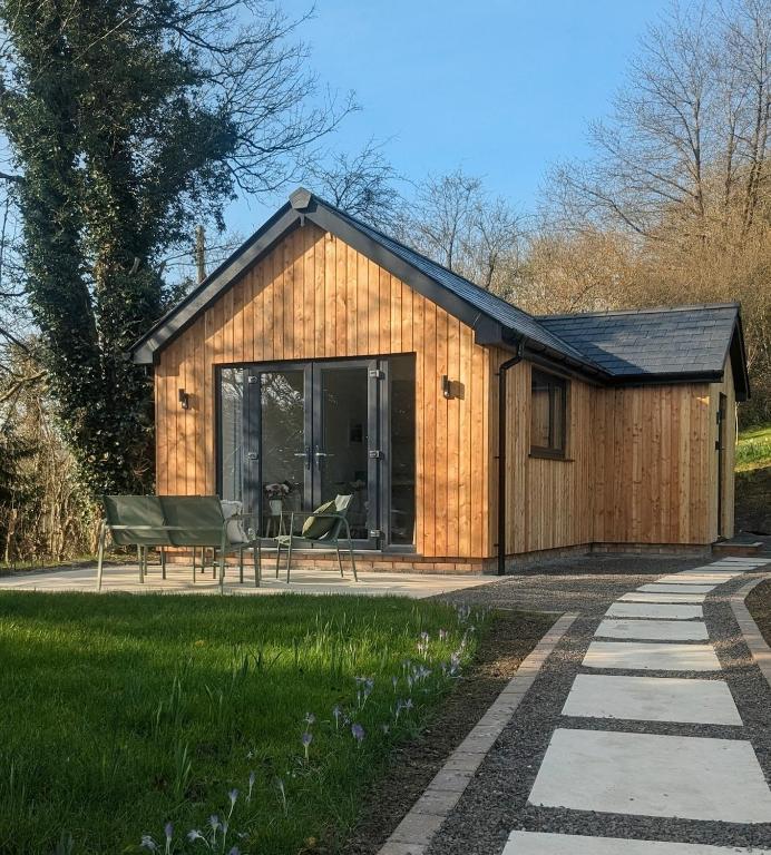 a small wooden shed with chairs and a patio at Yr Hen Stabl - The Old Stable in Llangerniew
