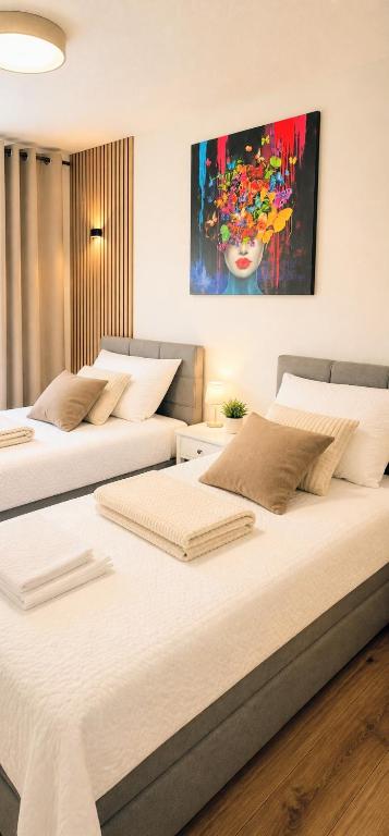 two beds in a bedroom with a painting on the wall at GADD Ferienwohnung 002 Glück an der Donau I Best Elegant Suite 24 h Check-In in Straubing