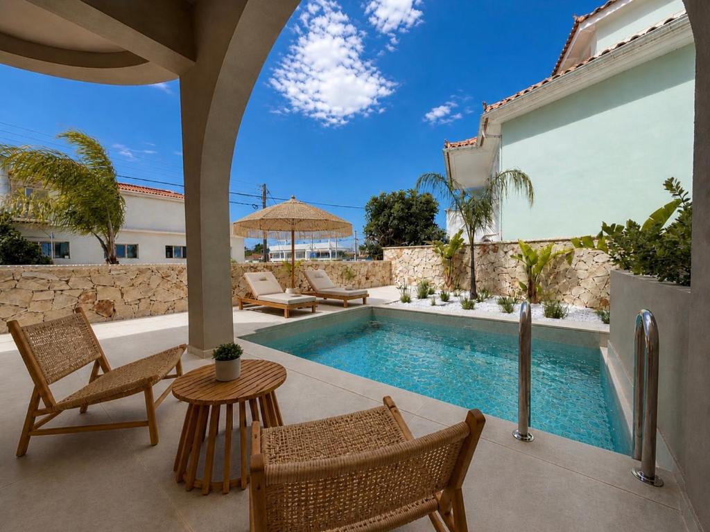 a patio with a pool and chairs and a table at ABATON Luxury Resort in Tsilivi