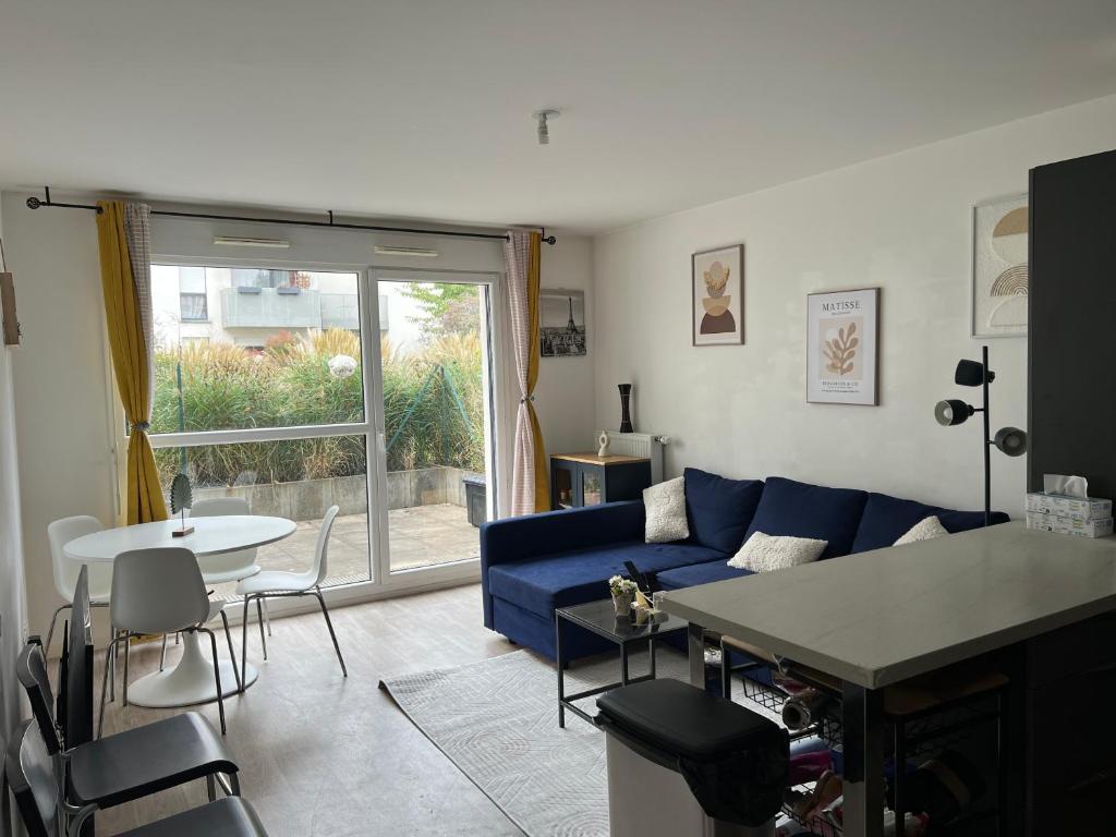 a living room with a blue couch and a table at Patty Home Stay in Carrières-sous-Poissy