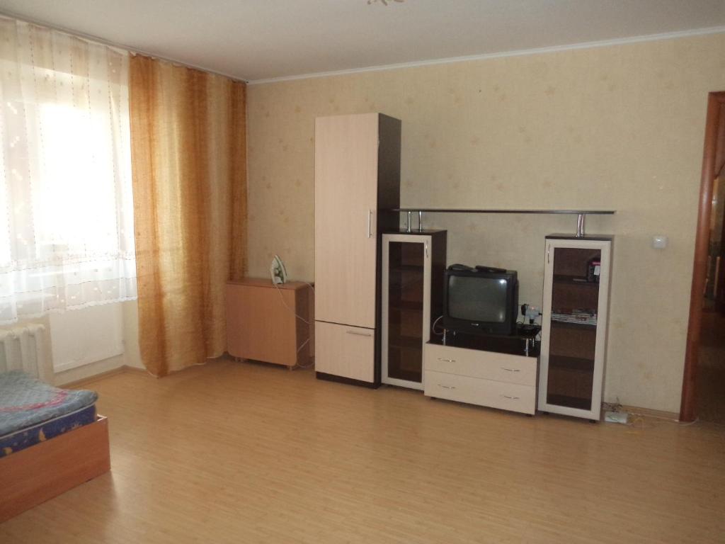 an empty living room with a television and a tv stand at Apartment on Komsomolskaya 8 in Kirov