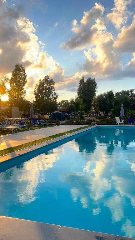 a large swimming pool with a cloudy sky in the background at Residence Toscano in Palmi