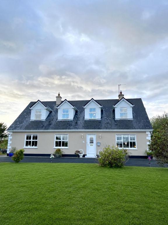 a white house with a black roof at Roskeen house in Tierna