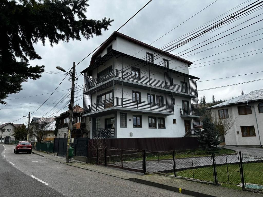 a tall white house with a car parked in front of it at Robert Urban Class in Gura Humorului