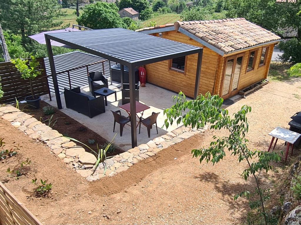 a small cabin with a roof and a table and chairs at Charmant chalet en bois - Ardèche in Joyeuse