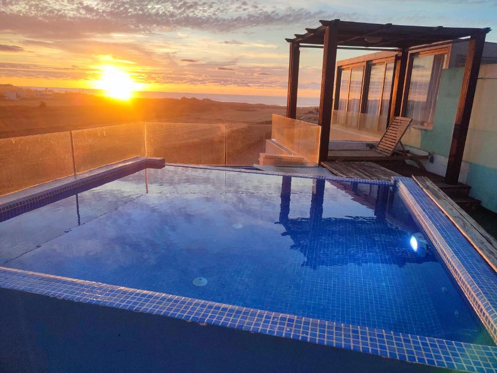 a swimming pool with the sunset in the background at appartments front mer in Bouznika