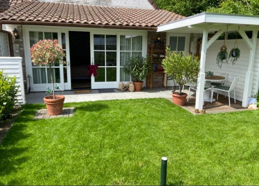 a small white house with a patio with plants at Gastenverblijf Het Groene Hart in Lanaken