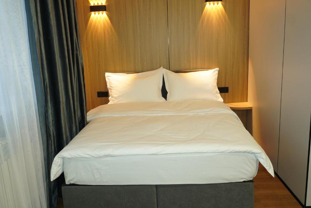 a bed with white sheets and pillows in a room at Alsun Hotel in Astana