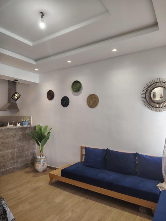 a living room with a blue couch and clocks on the wall at kelibia maison a 170 m de la plage Ezzahra in Kelibia