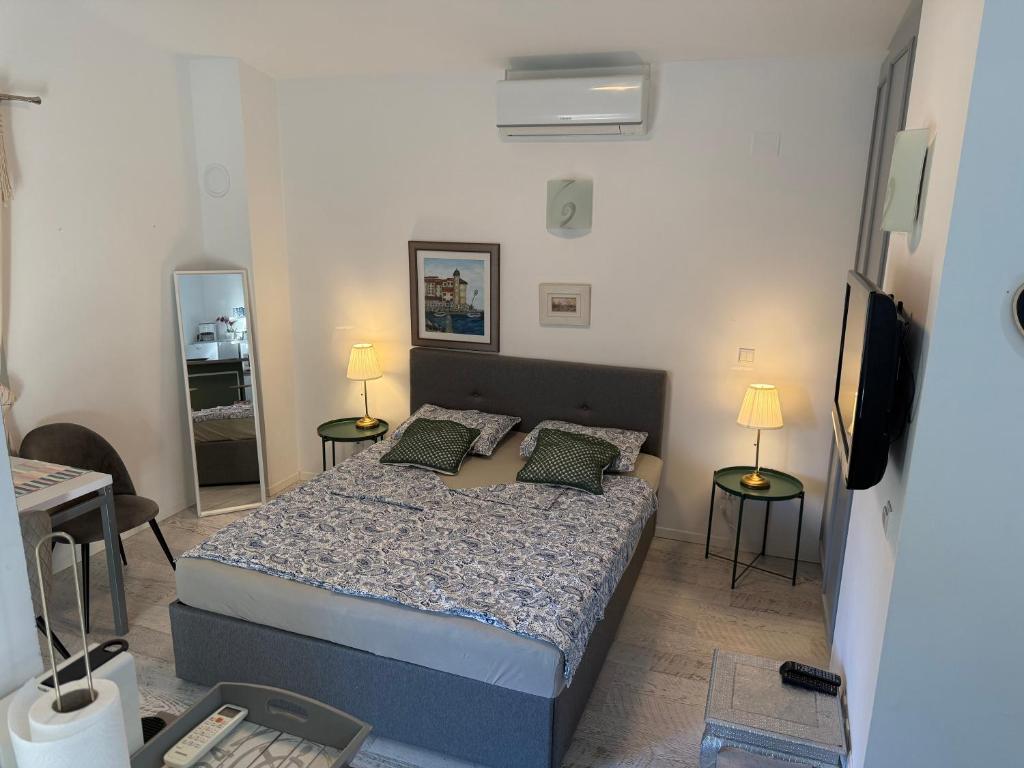 a bedroom with a bed and two tables and a television at Rab Studio first floor 32m2 in Kampor