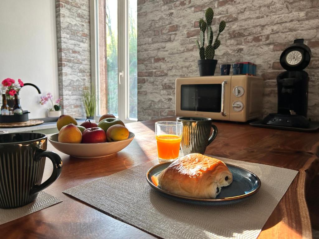 a table with a plate of food and orange juice at Cocon romantique Jardin de la princesse idéal couple Calme & nature Vosges in Senones