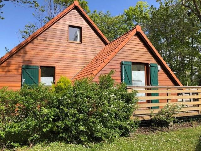 a large wooden house with green windows and a fence at Chalet confortable à Berck-sur-Mer in Berck-sur-Mer