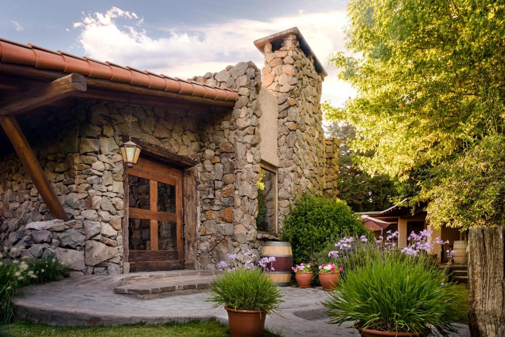 a stone house with potted plants in front of it at Lares De Chacras in Chacras de Coria