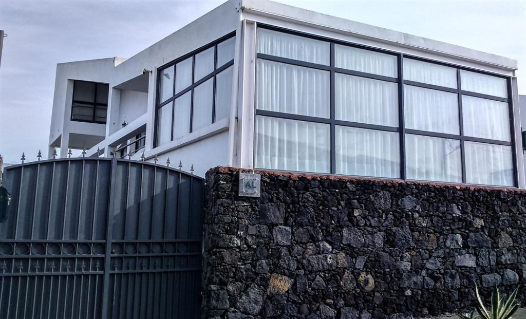 a house with a black fence and a stone wall at Surf & Guest Lorena´s House in Ribeira Grande