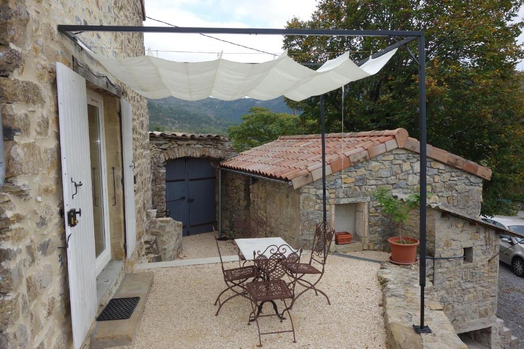 d'une terrasse avec une table et des chaises sous un parasol blanc. dans l'établissement Gite Les Douces, à Vesseaux