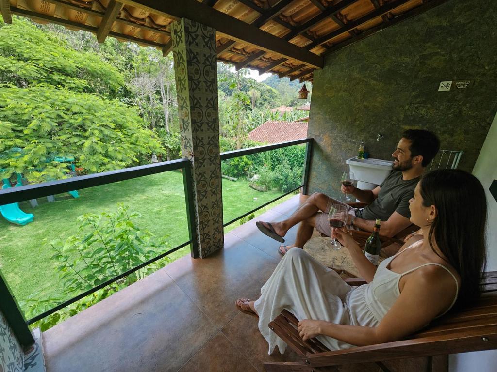 a group of people sitting on a porch drinking wine at Rio Sereno Suítes Comfort - Lumiar in Lumiar