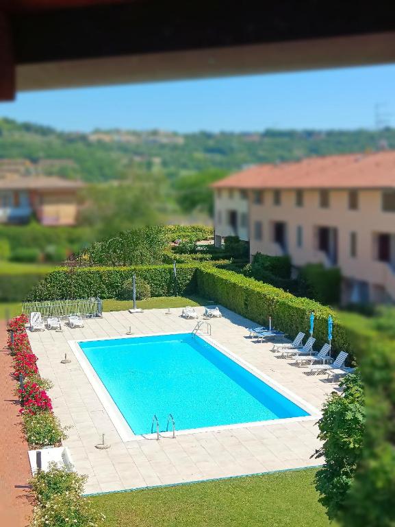 an overhead view of a swimming pool with chairs and a building at Appartamento Orchidea Garda in Garda