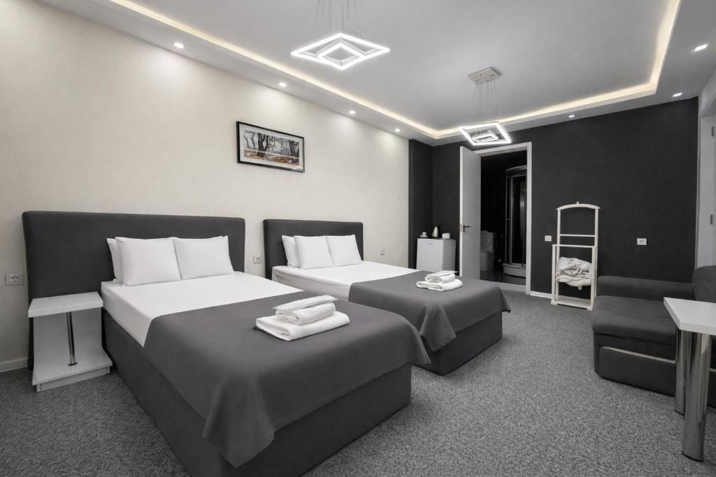 a hotel room with two beds and a chair at DavidL Hotel Tbilisi in Tbilisi City