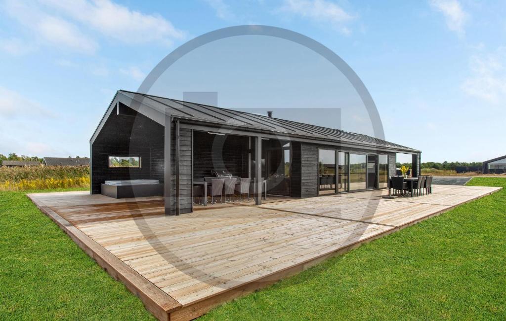 a black house with a wooden deck in a field at Awesome Home In Jerup With Sauna in Jerup