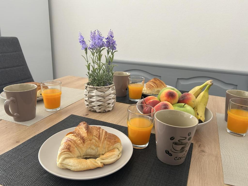 a table with a plate of bread and fruit and glasses of orange juice at En famille au cœur des Vosges aux portes de l'Alsace, Vue château in Senones