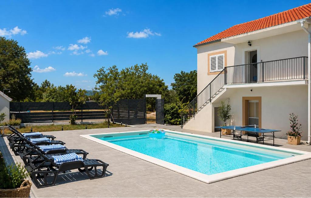 a pool with chairs and a table next to a house at Amazing Home In Dugobabe in Dugobabe