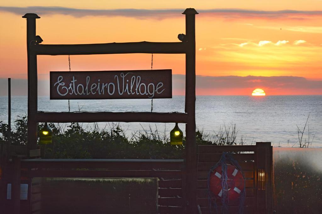 a sign in front of the ocean with the sunset at Pousada Estaleiro Village - Frente Mar in Balneário Camboriú