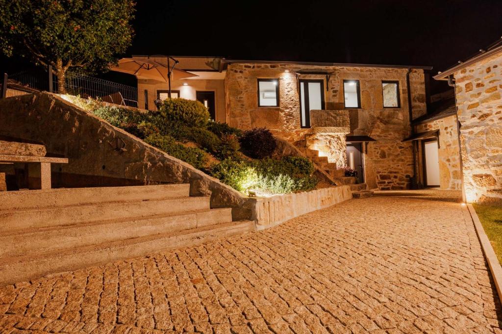 a house with a brick walkway and stairs at night at Os Paizinhos do Arrujo in Cinfães