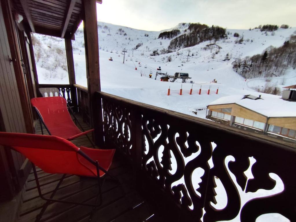 a red chair on a balcony with a ski slope at Le Carré Coloré in Ustou