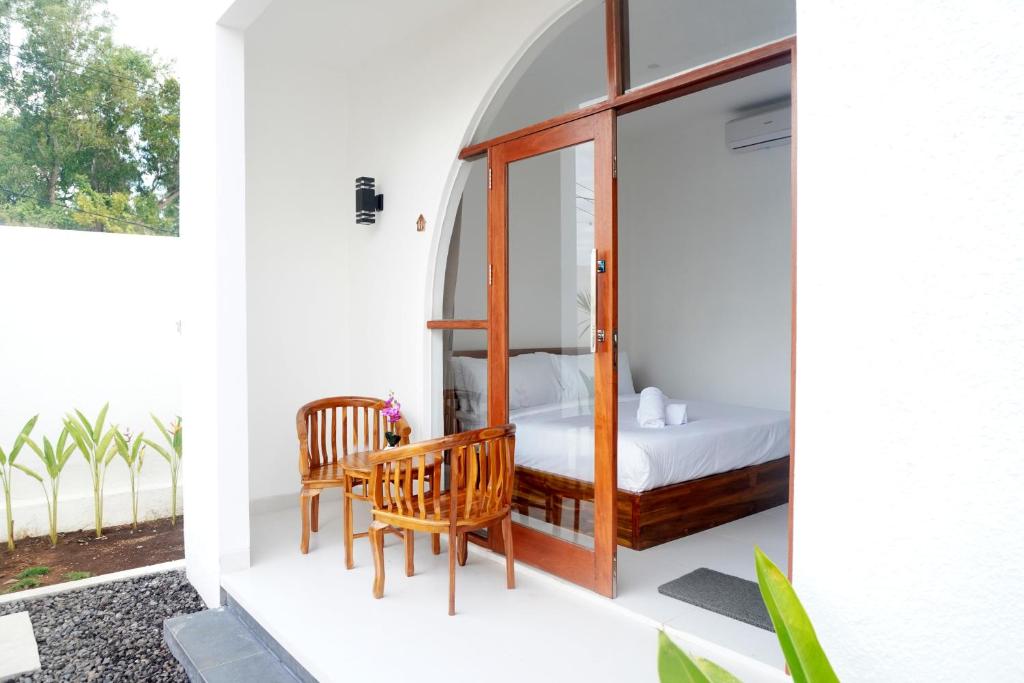 a room with a bed and two chairs on a balcony at Home Riki in Badung