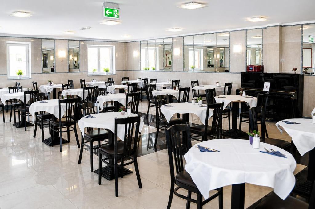 a dining room with white tables and chairs at Hotel Donaustadt Kagran - at Metro U1 in Vienna