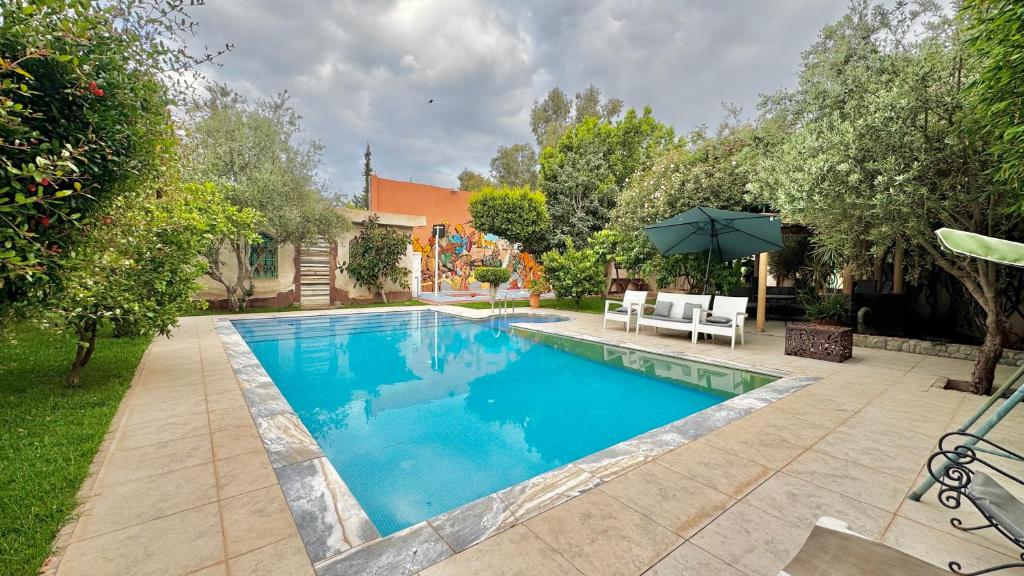 a swimming pool in a yard with an umbrella at Villa familiale avec piscine privée sans vis à vis in Oulad Raho