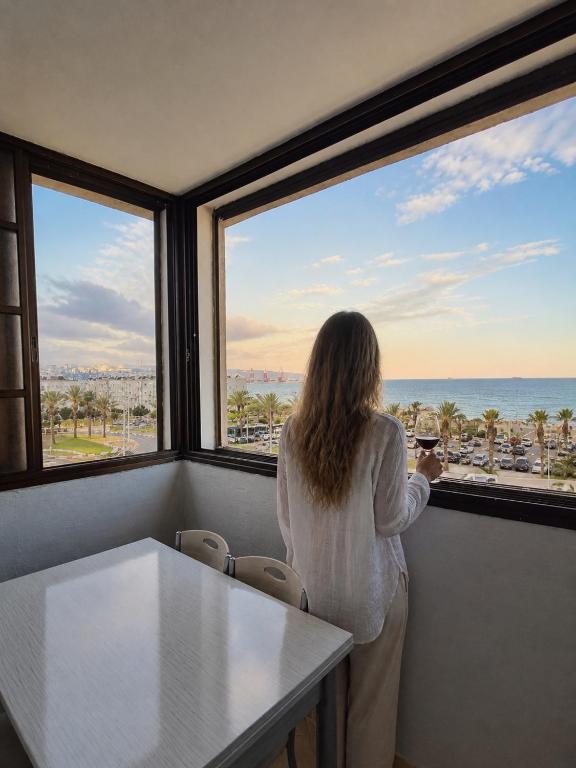 a woman looking out of a window at the ocean at Sea view panorama 62 in Haifa