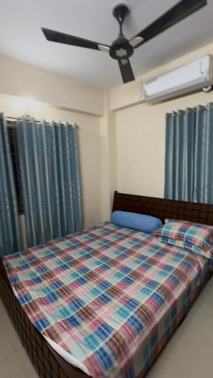 a bedroom with a bed and a ceiling fan at Stay with Comfort in Cox's Bazar