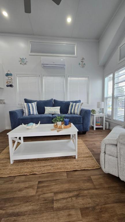 a living room with a blue couch and a white coffee table at Happier in the Keys Waterfront Tiny Home in Key Largo